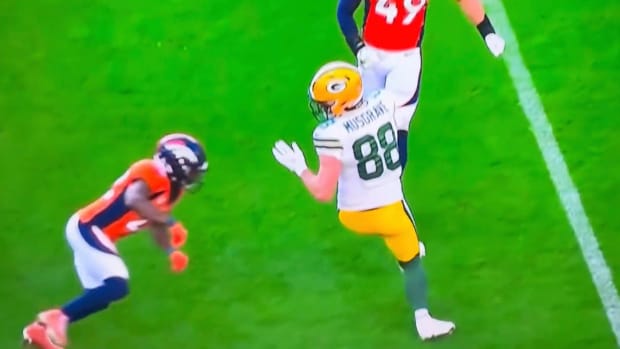 Denver Broncos safety prepares to hit Green Bay Packers tight end Luke Musgrave in an Oct. 22, 2023 NFL game.
